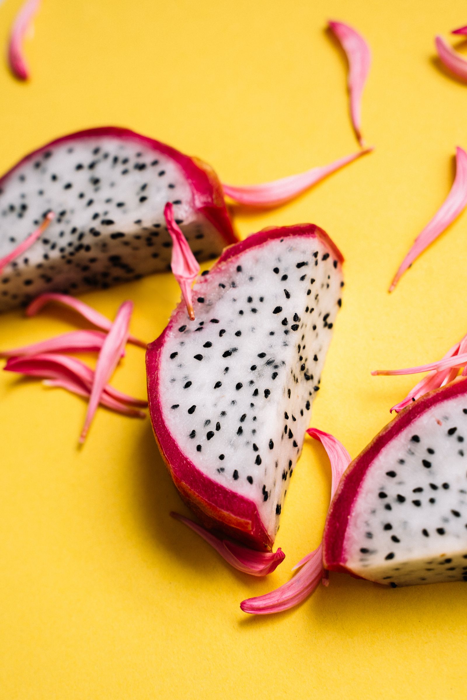 White-fleshed dragon fruit cut open on a yellow surface