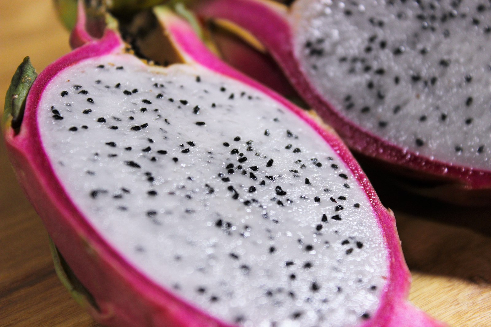 Close-up of a halved white-flesh dragon fruit with black seeds.