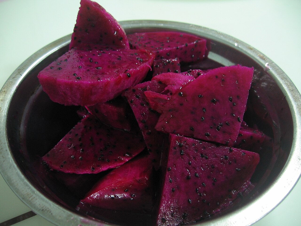 Red-flesh dragon fruit cubes and a wedge in a small bowl.