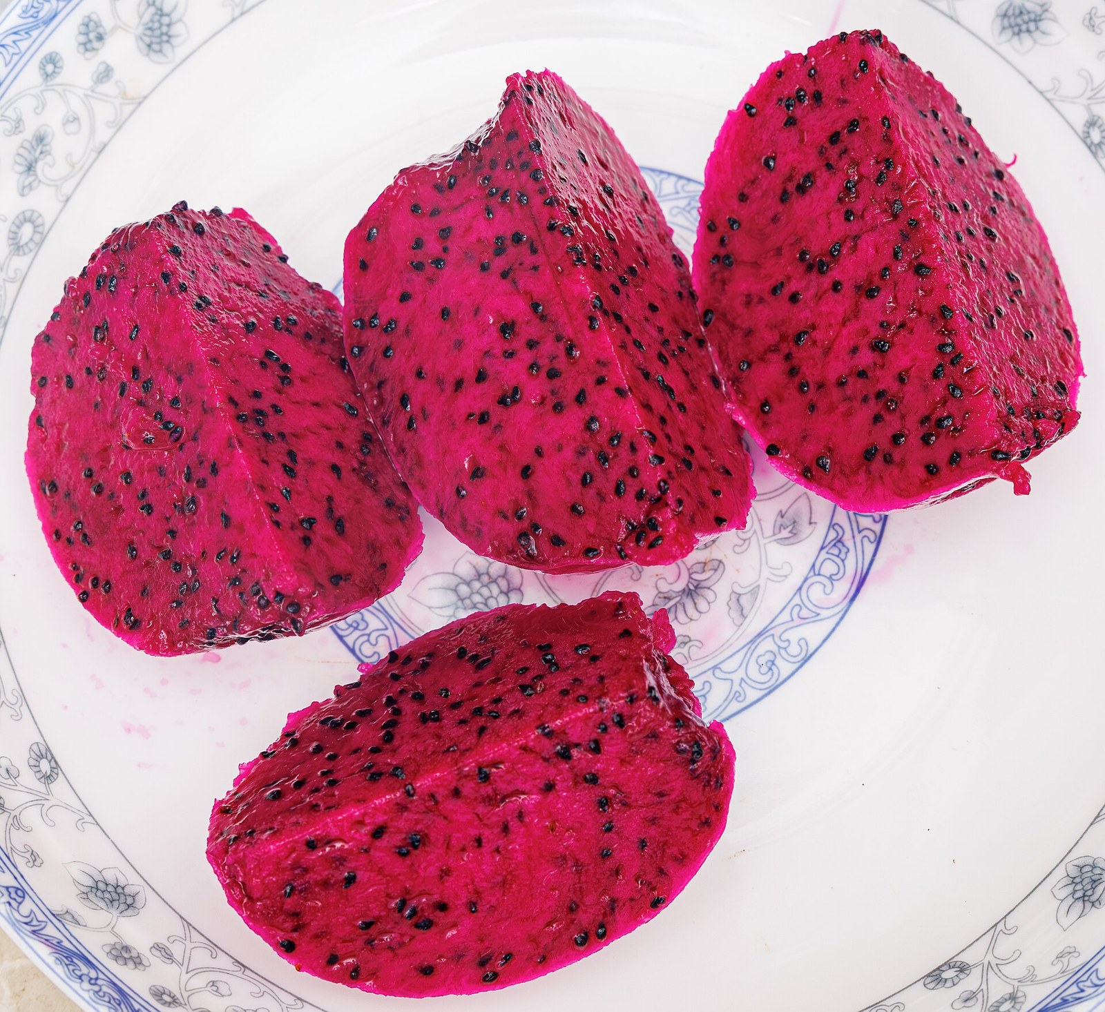 Red-flesh dragon fruit wedges arranged on a plate.