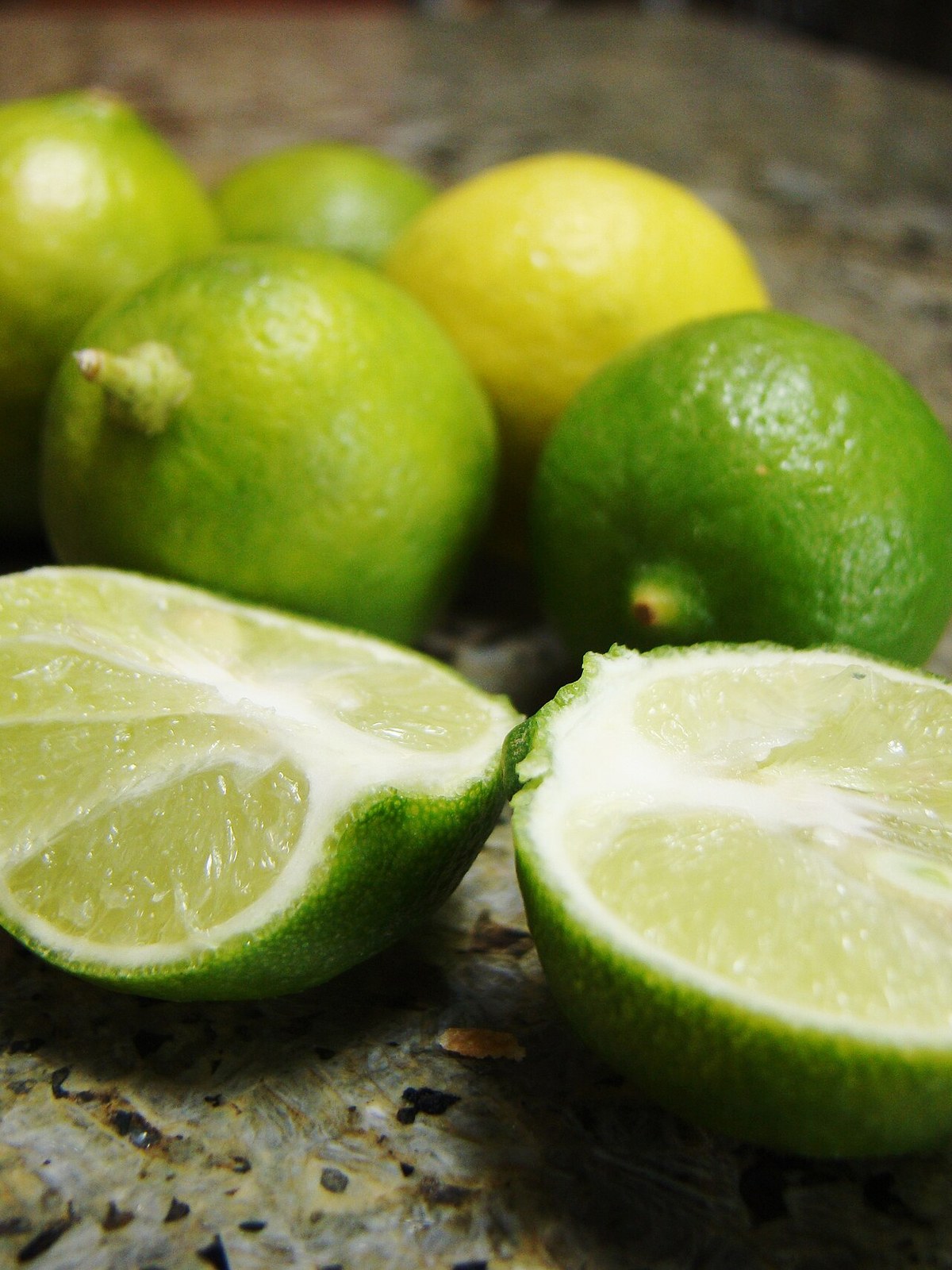 Fresh green limes and cut halves on a kitchen counter.