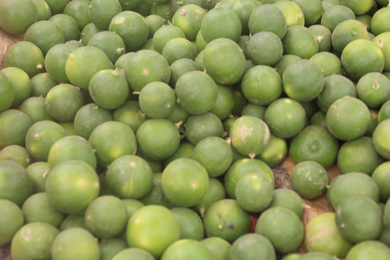 Loose green limes piled at a produce market.