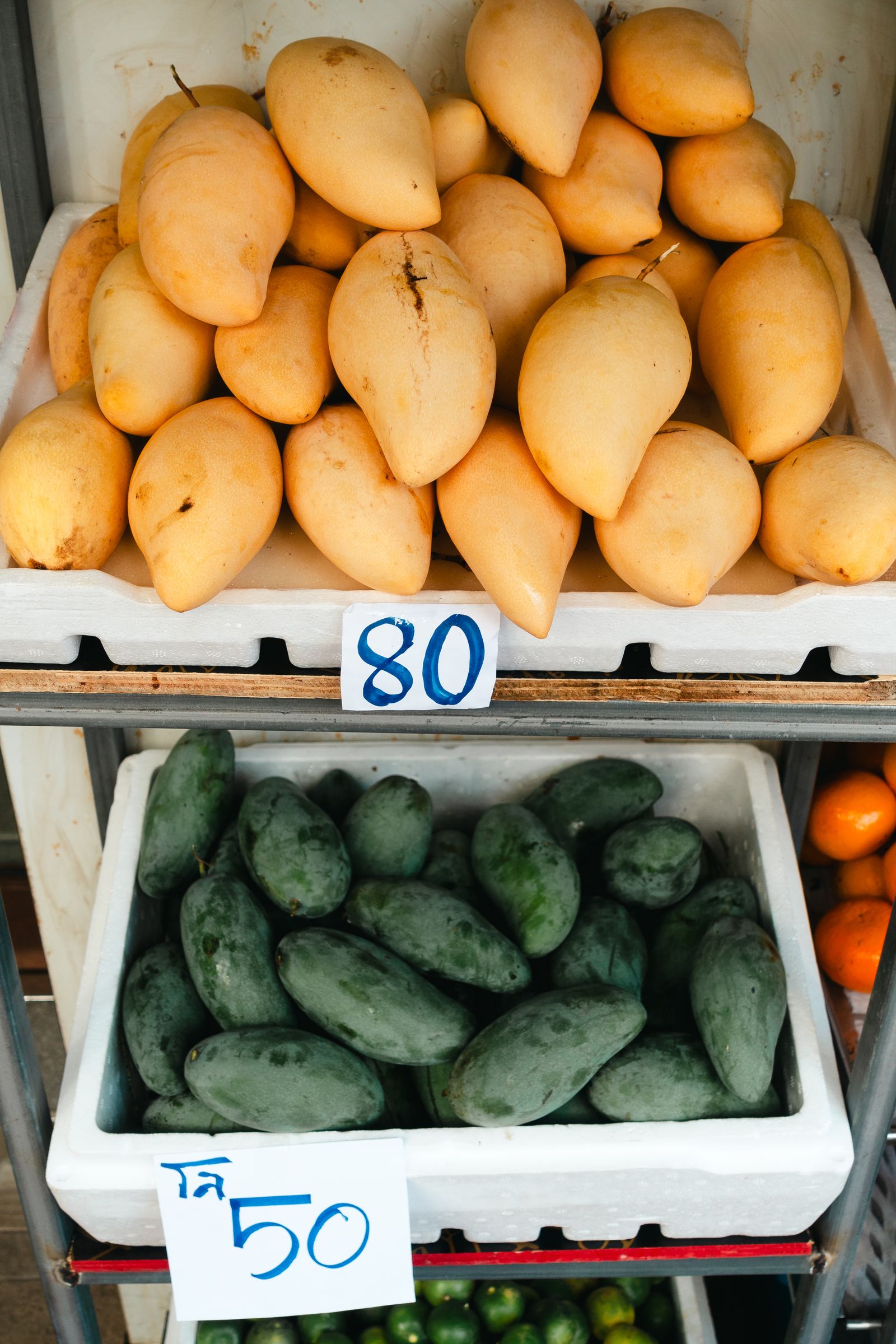 Yellow and green mangoes arranged in market crates