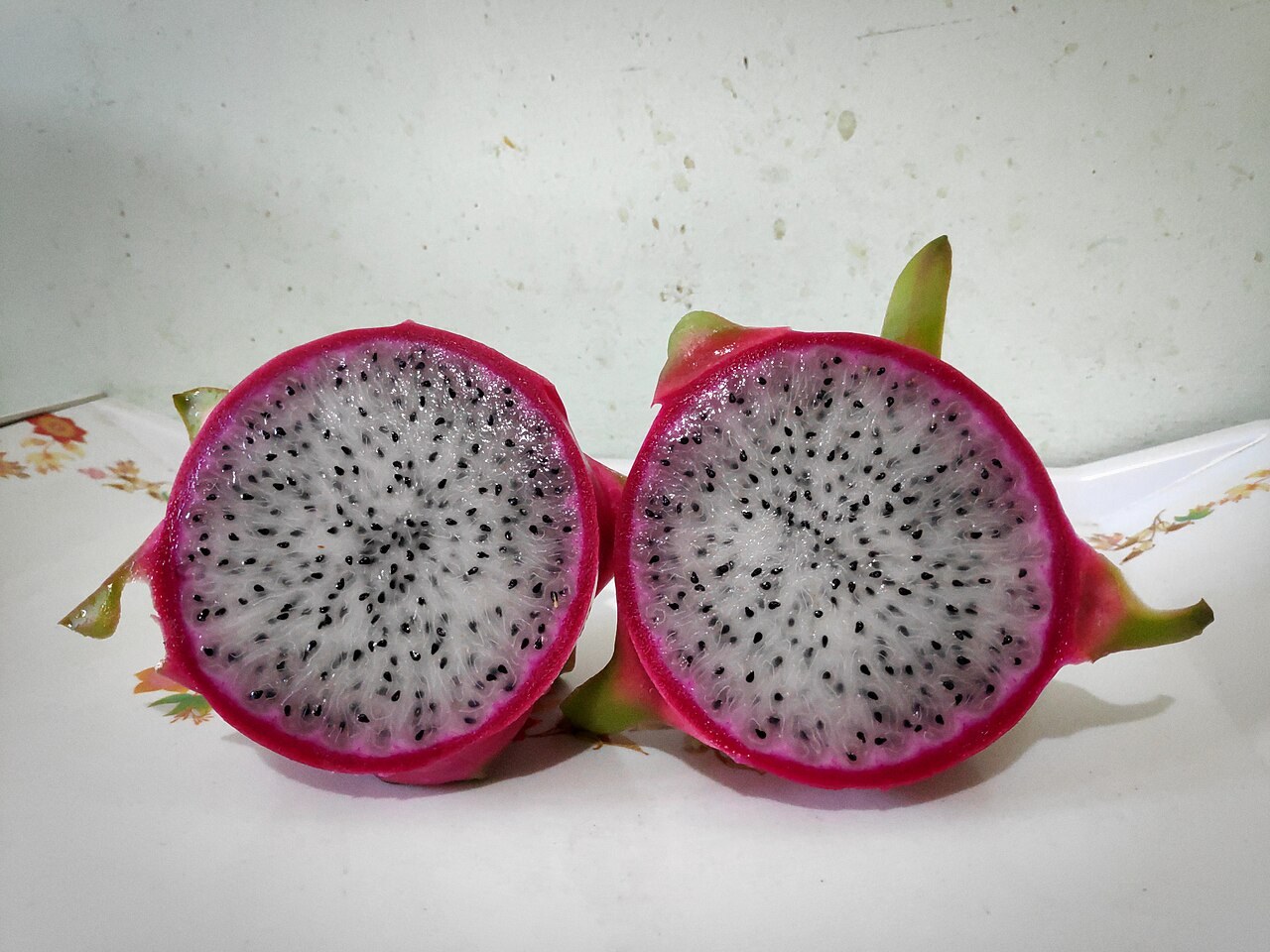 Two halves of a white-flesh dragon fruit on a light surface.