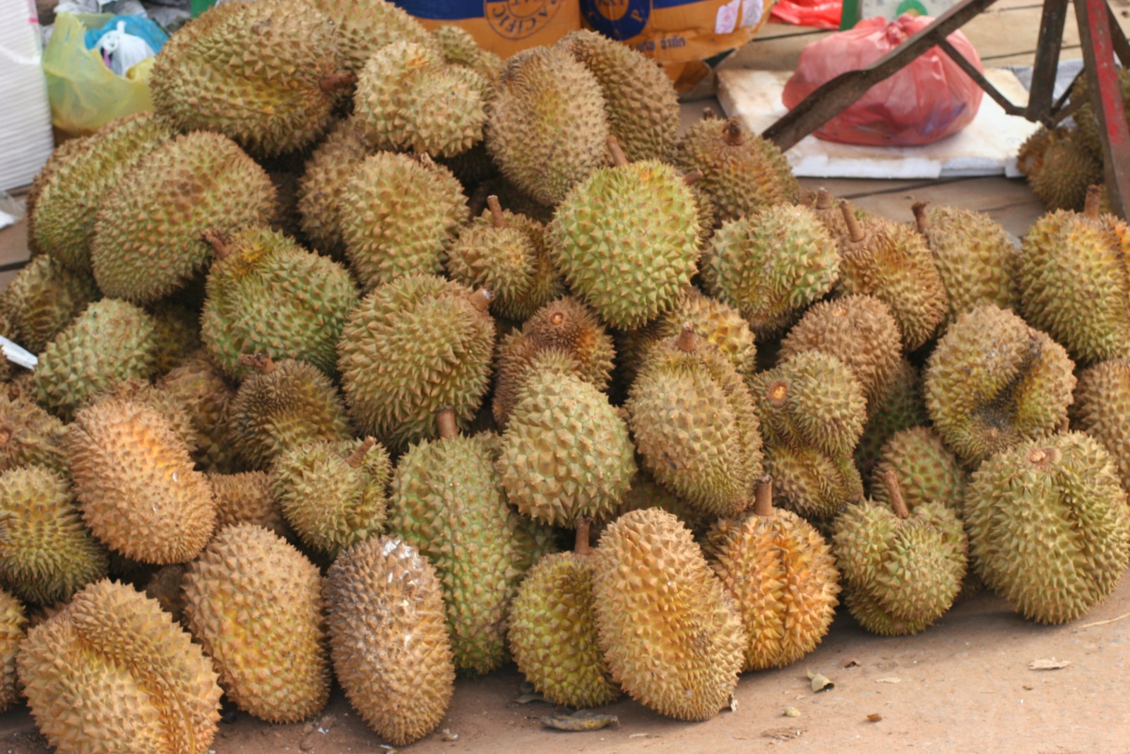A large heap of whole durians on a market display.