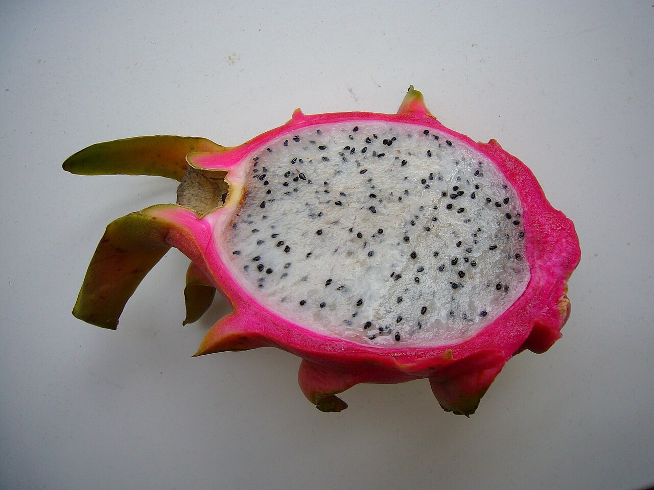 A halved white-flesh dragon fruit on a pale surface.