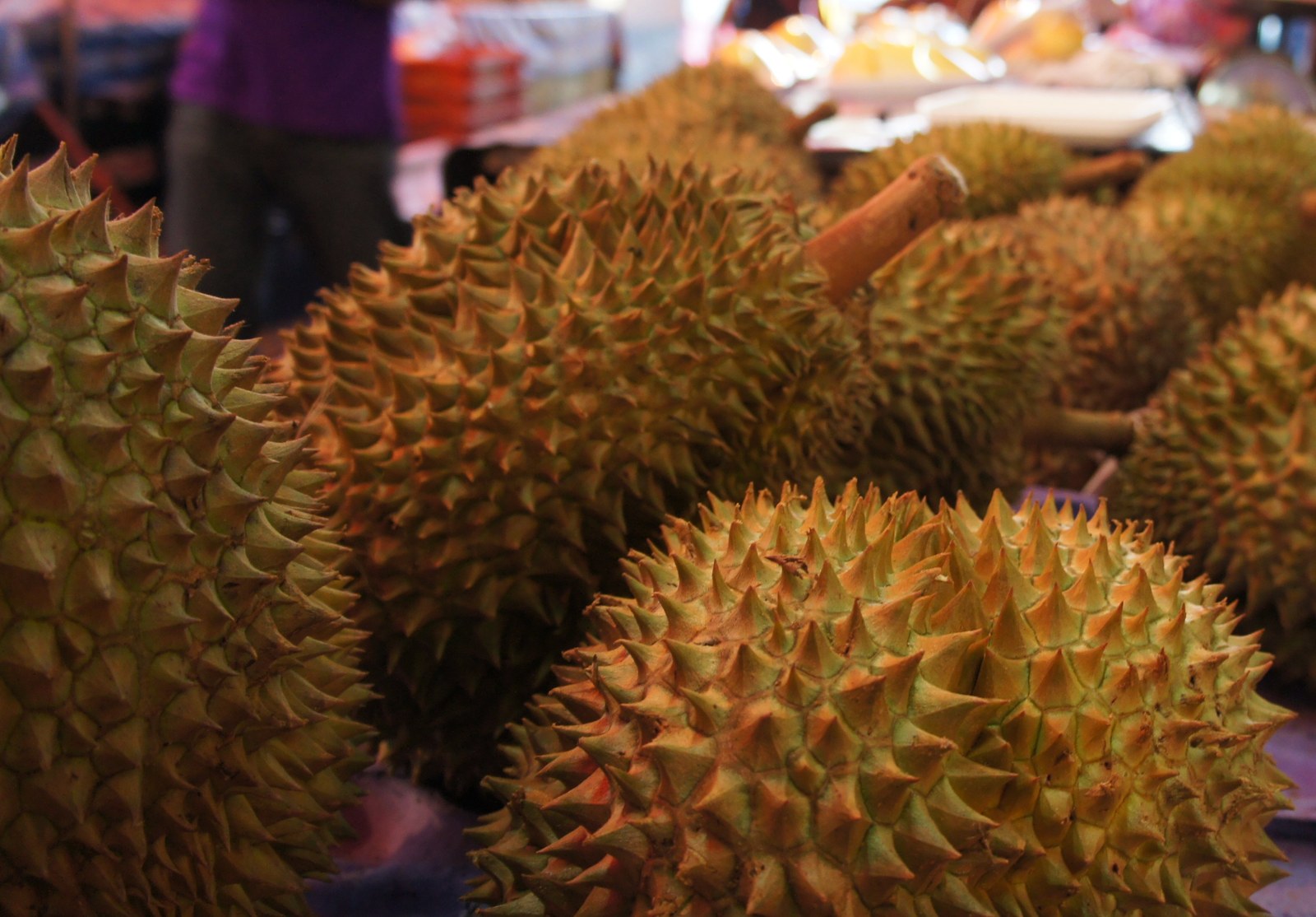 Ripe whole durians displayed close together at a market.