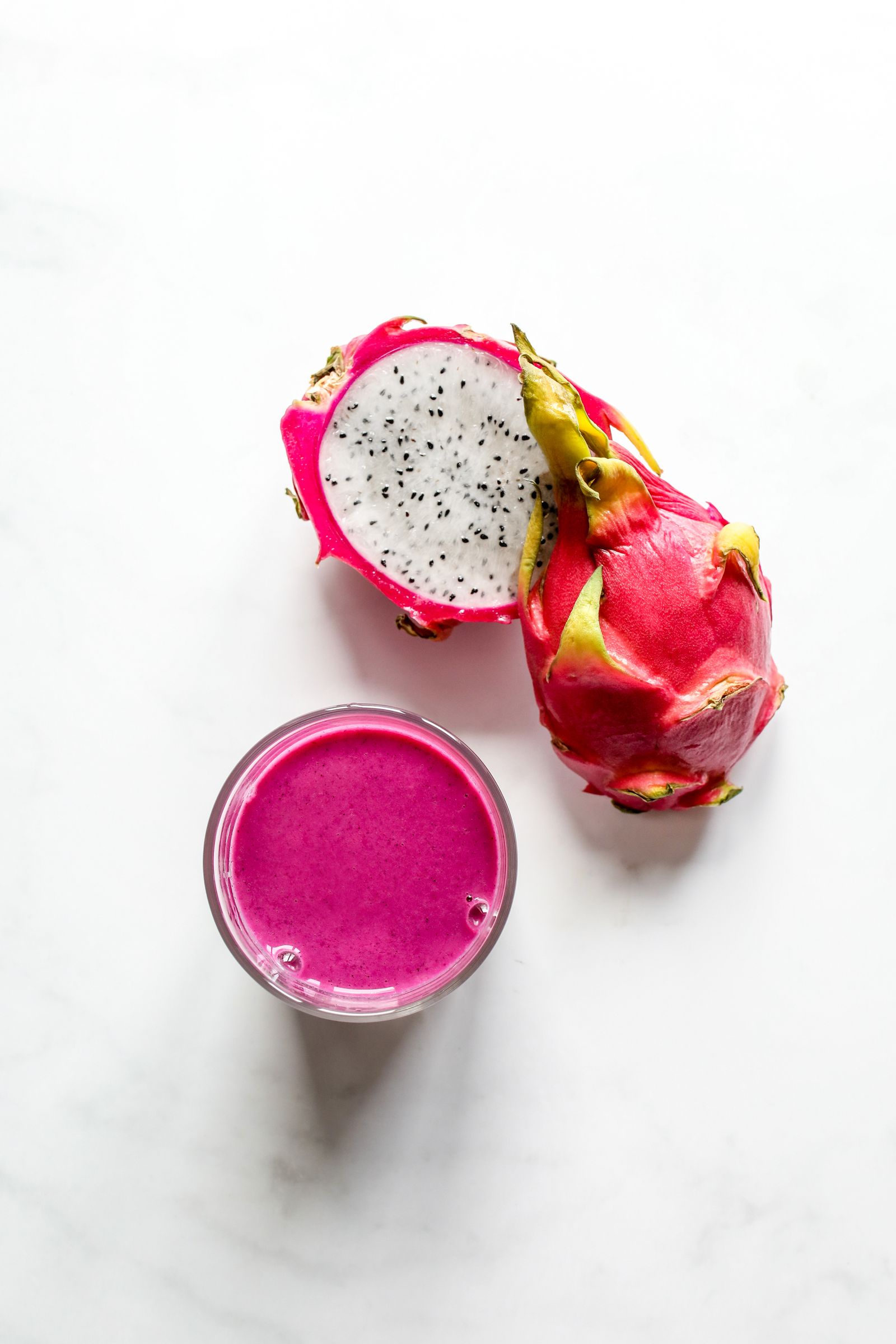 Pink smoothie beside sliced dragon fruit