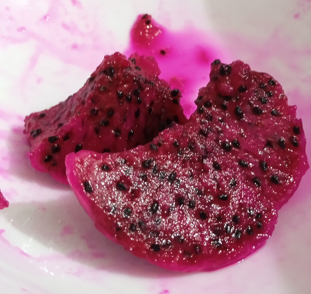 Fresh red-flesh dragon fruit pieces with black seeds.