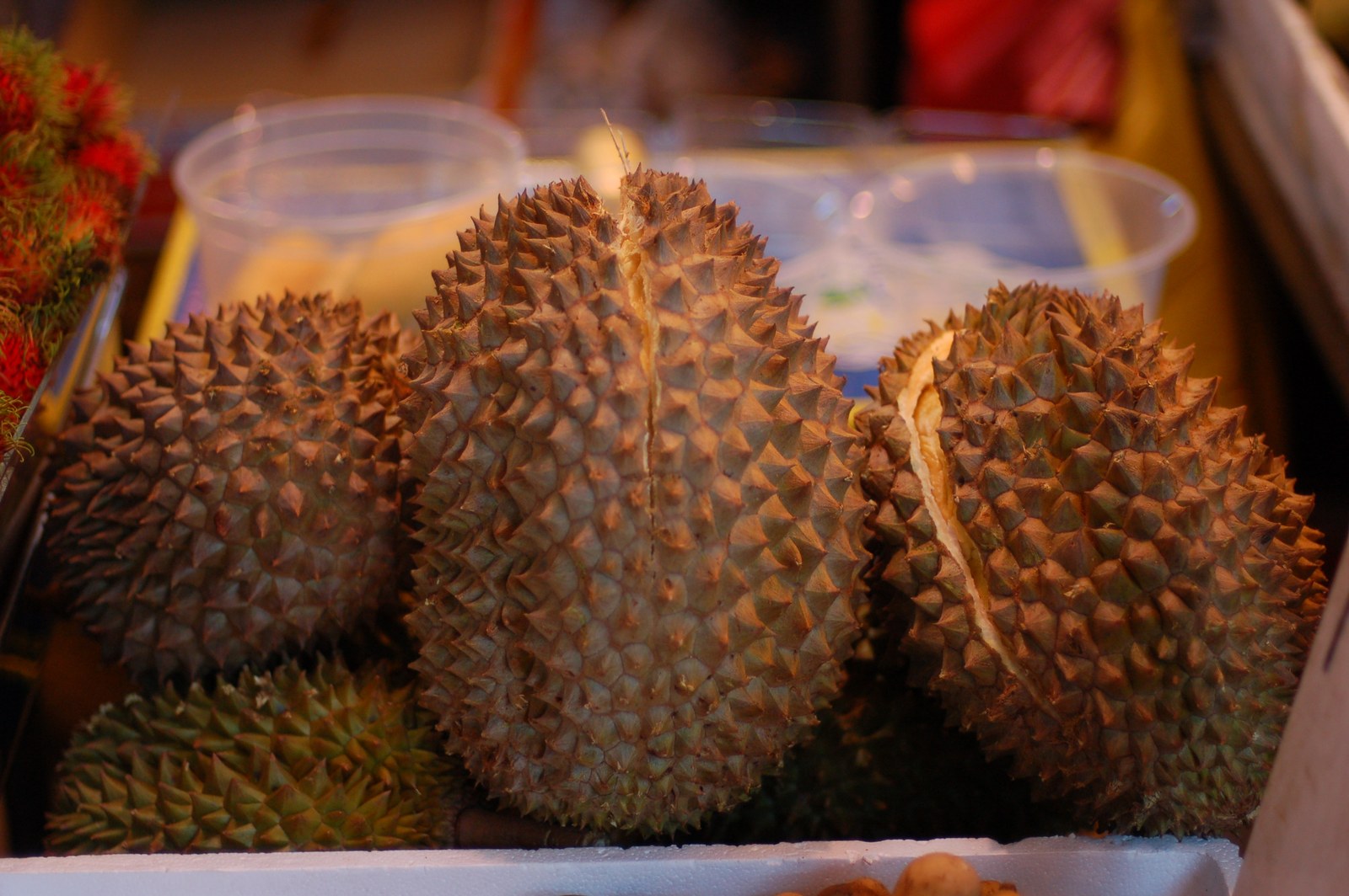 Three whole durians arranged on a market counter.