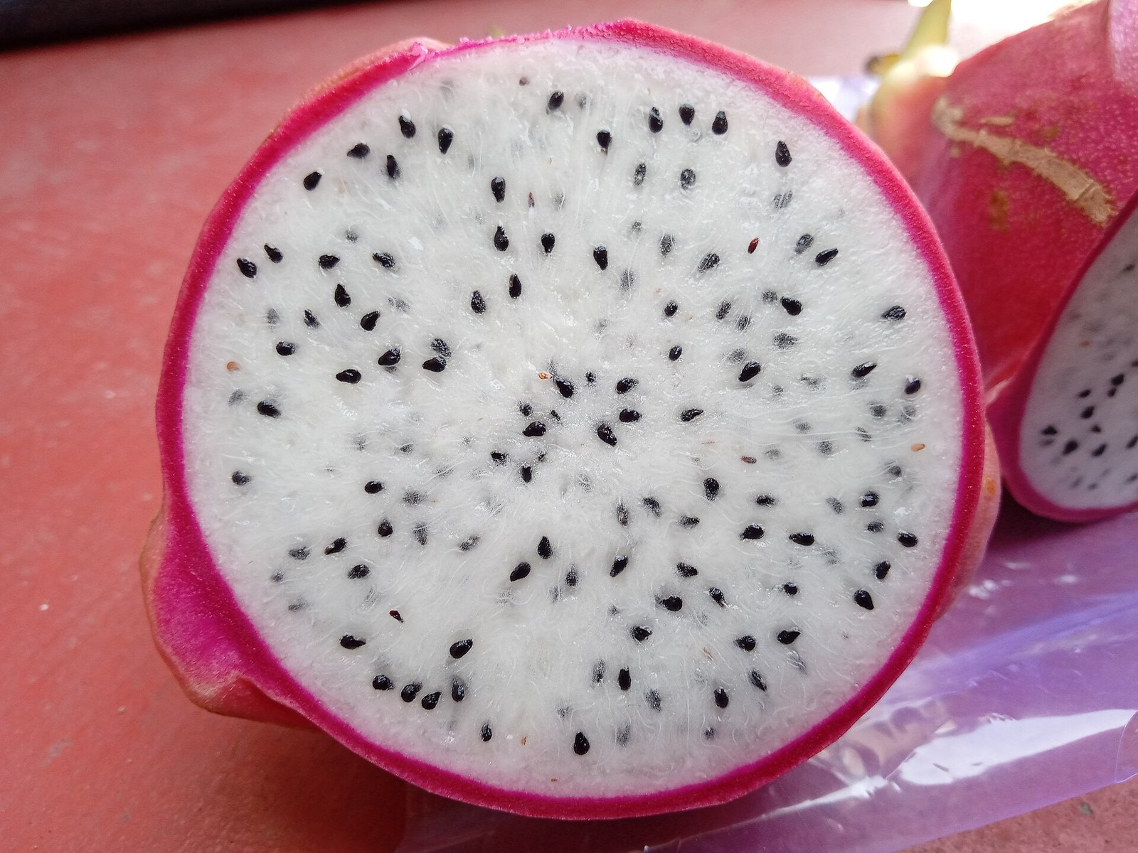 Close-up of a white-flesh dragon fruit cut open, showing black seeds.