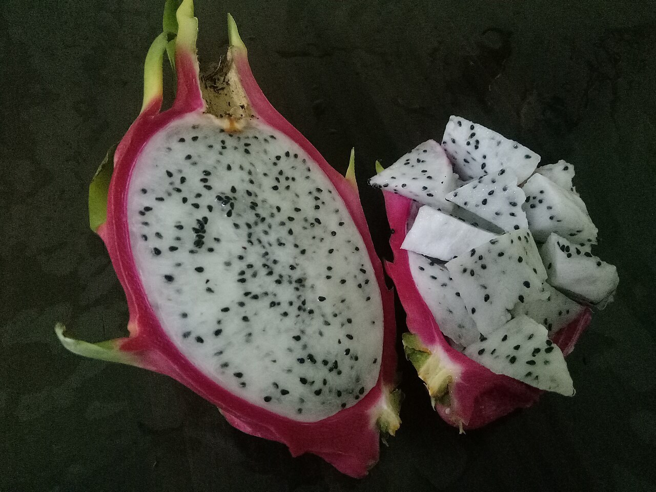 A cut white-flesh dragon fruit with small black seeds.