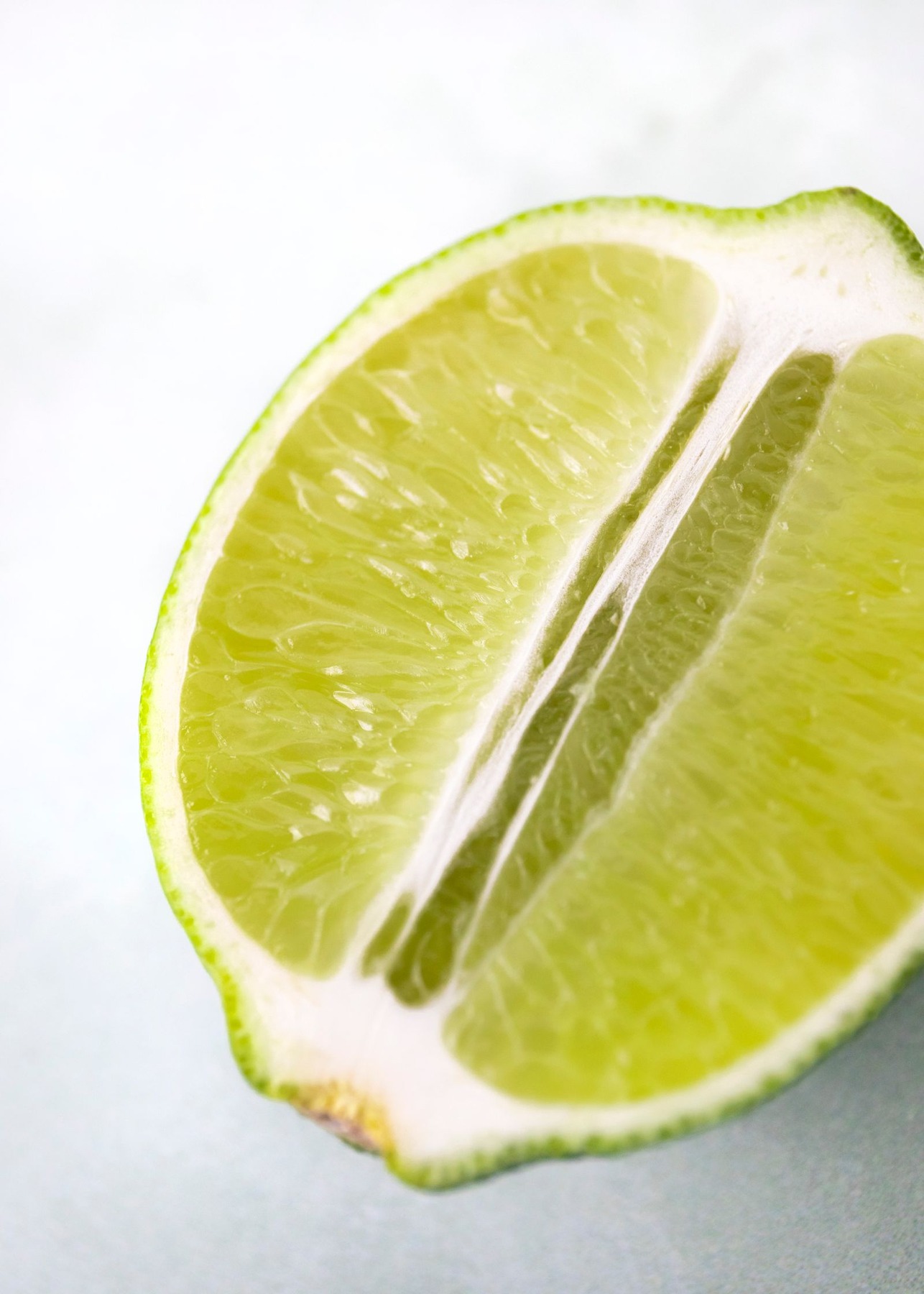 Close view of a cut lime showing its rind and juicy flesh.
