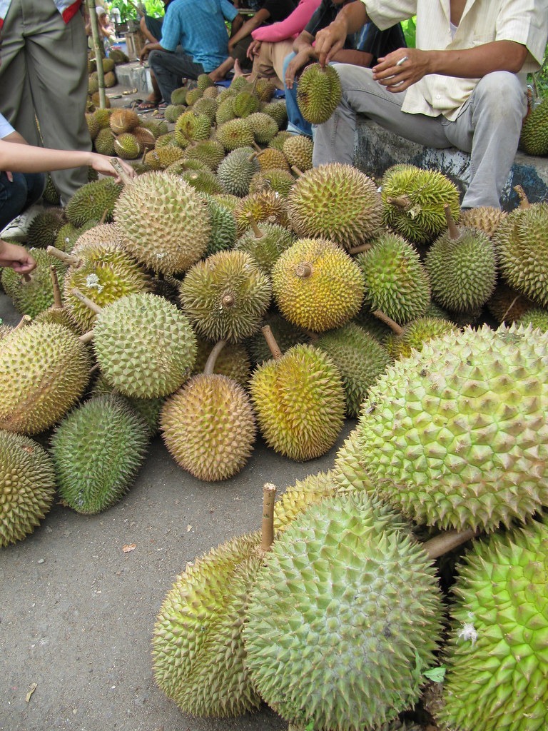 Sầu riêng nguyên trái xếp thành đống tại chợ nông sản.