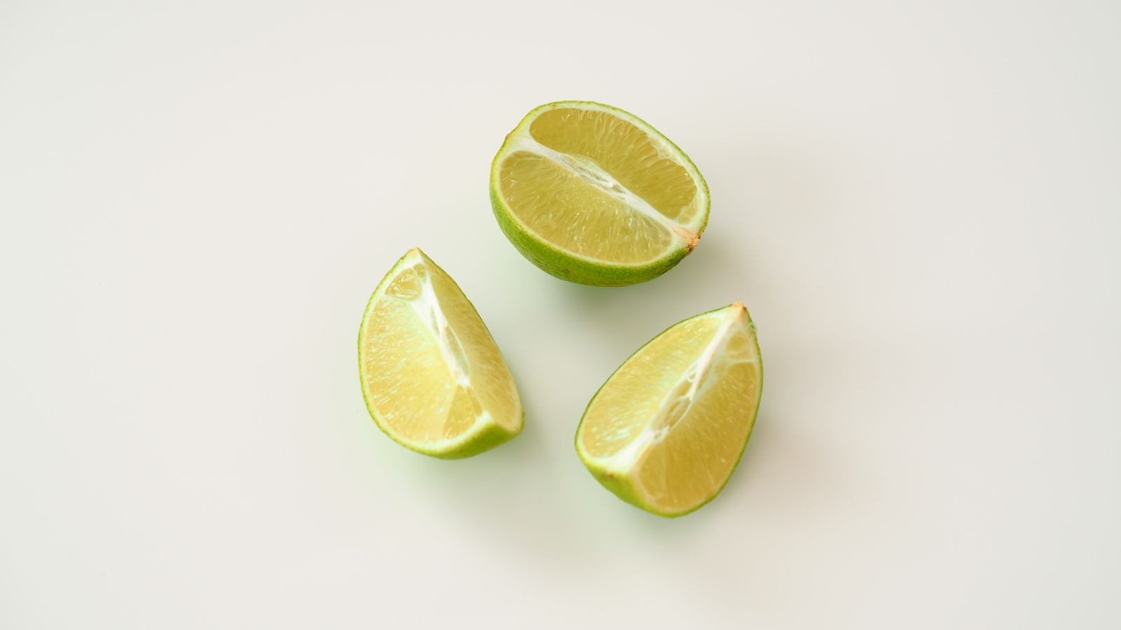 A lime half and two lime wedges on a light background.