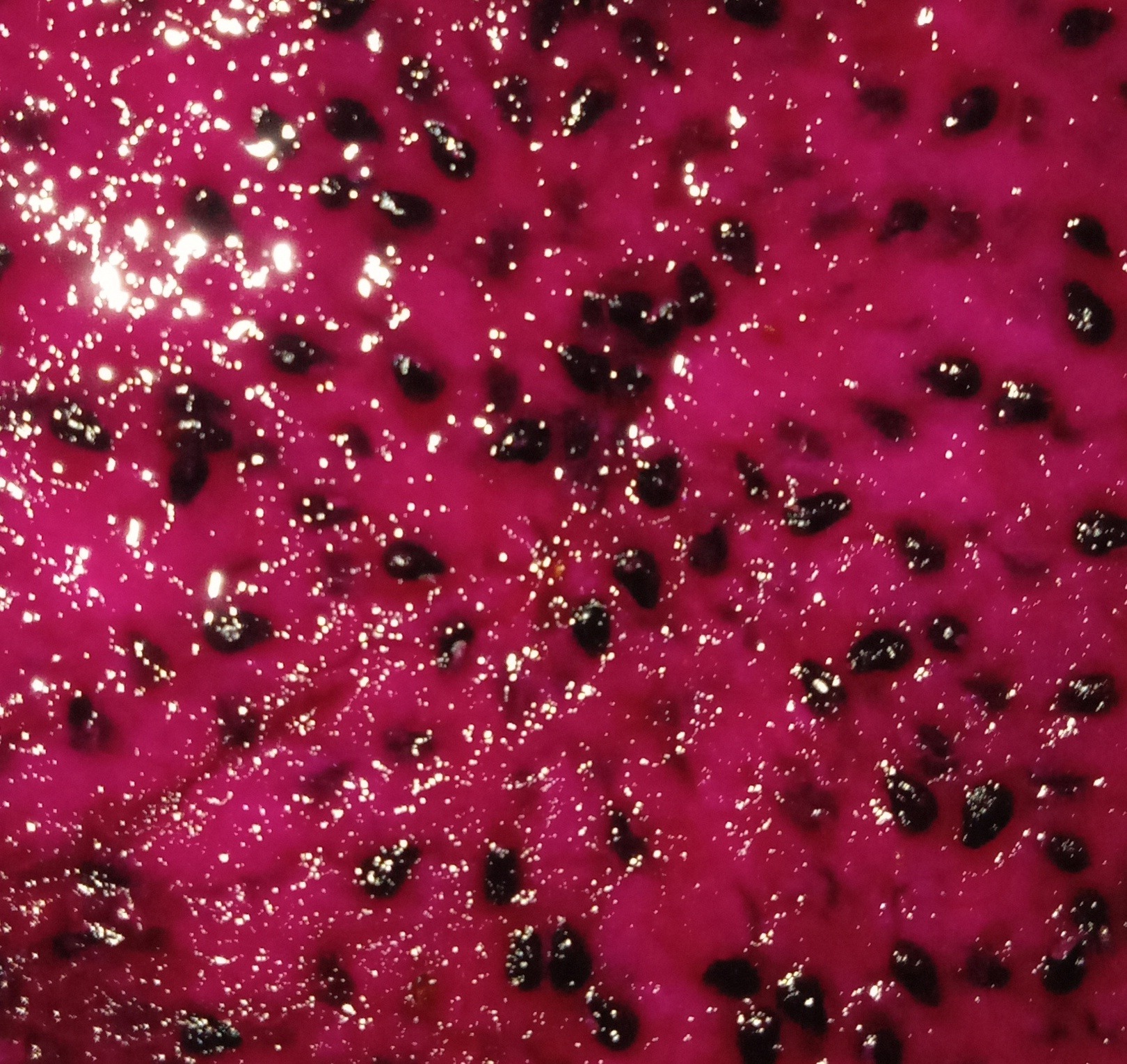 Close-up of red dragon fruit flesh with small black seeds.