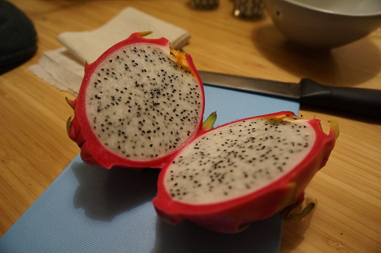 Two halves of a white-flesh dragon fruit on a cutting board.