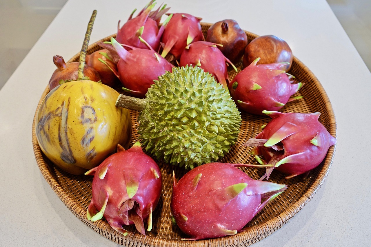 A basket of tropical fruit containing durian and dragon fruit.